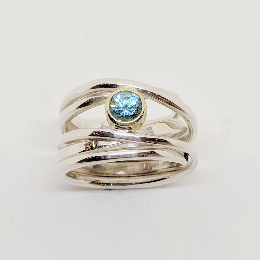 Sterling Silver OneFooter Ring, set with 5mm Blue Zircon, set in 18kt. Yellow Gold by Dorothée Rosen at The Avenue Gallery, a contemporary fine art gallery in Victoria, BC, Canada.