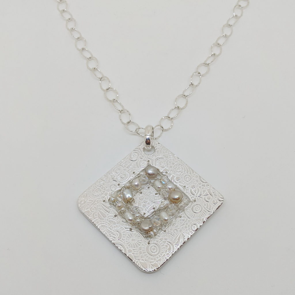 Textured Diamond-Shape Pendant with Crocheted Wire, Pearls & Swarovski Crystals by Veronica Stewart at The Avenue Gallery, a contemporary fine art gallery in Victoria, BC, Canada.