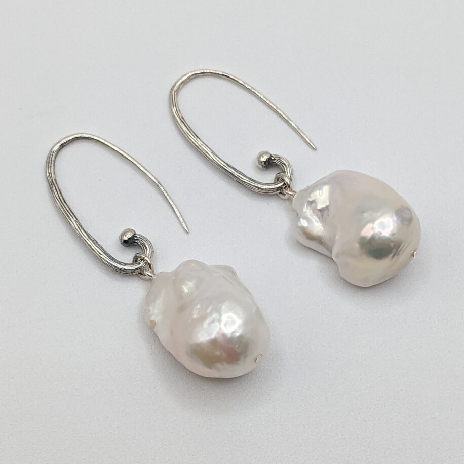 White Baroque Pearl Earrings with Oval Hammered Hoops by Val Nunns at The Avenue Gallery, a contemporary fine art gallery in Victoria, BC, Canada.