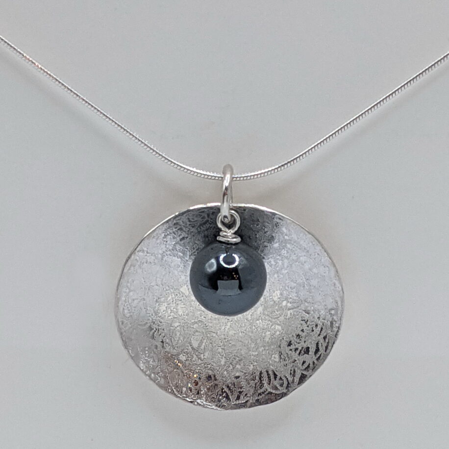 Scribbled Large Concaved Silver Disc Necklace with Hematite by Chi's Creations at The Avenue Gallery, a contemporary fine art gallery in Victoria, BC, Canada.